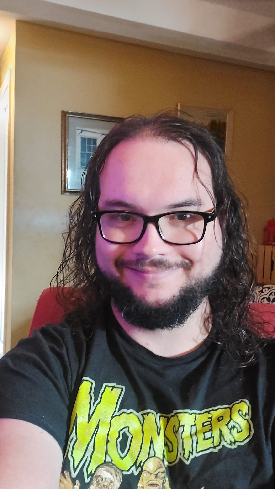 A man with long dark hair and a beard sits in a computer chair, photo 5